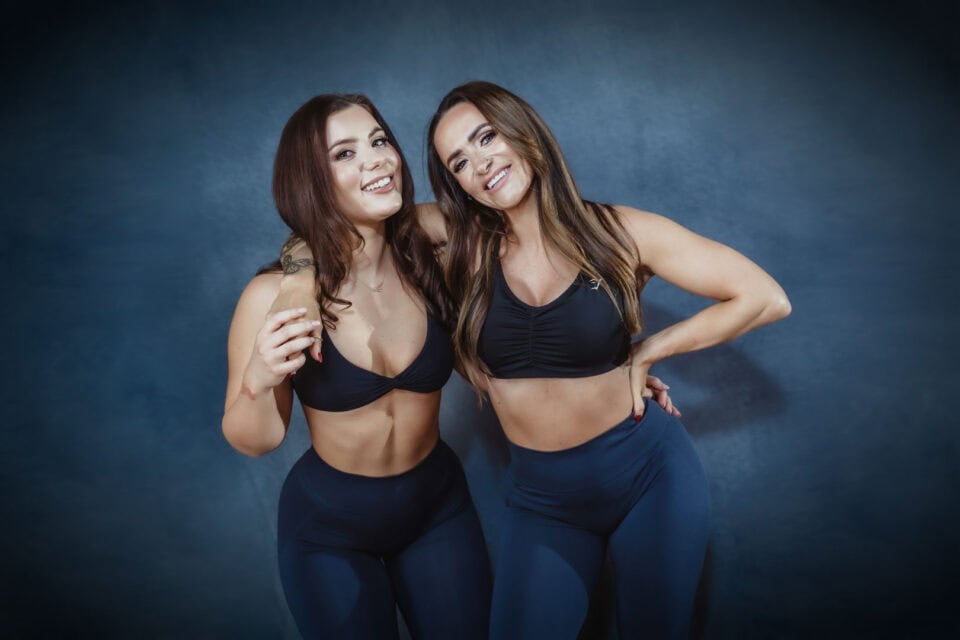 Stacey Cruickshank and Melanie Andersen of Thrive Coaching Online wearing matching gym outfits, chalkboard background